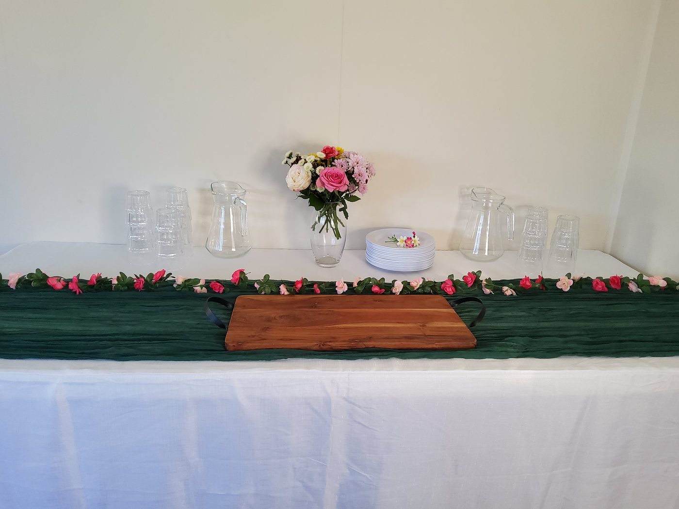 Party package styled table setup with green runner and floral garland
